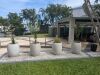 Four Bolla Tall Round Planters arranged in a gravel garden bed alongside the walkway at a Gold Coast waterfront property.