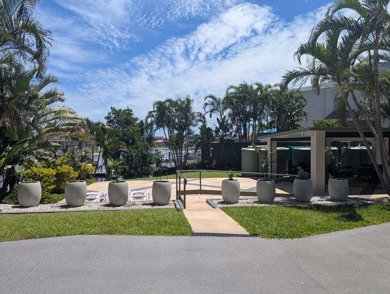 A wide view of the full installation showing all eight Bolla planters flanking the central terrace, with the waterfront canal visible in the background.