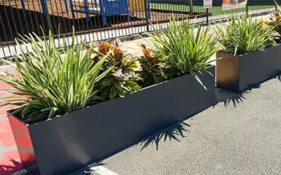 St. Josephs Tobruk Memorial School Uses Charcoal Trough Planters to Differentiate Walkway and Parking Lot