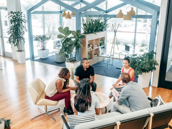 Group of coworkers in a modern, plant-filled office space.